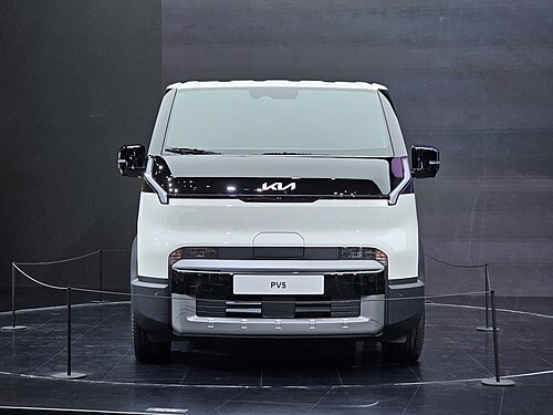 Kia PV5 Cargo รถตู้ไฟฟ้าสีขาว มุมตรงด้านหน้า จัดแสดงบนเวที