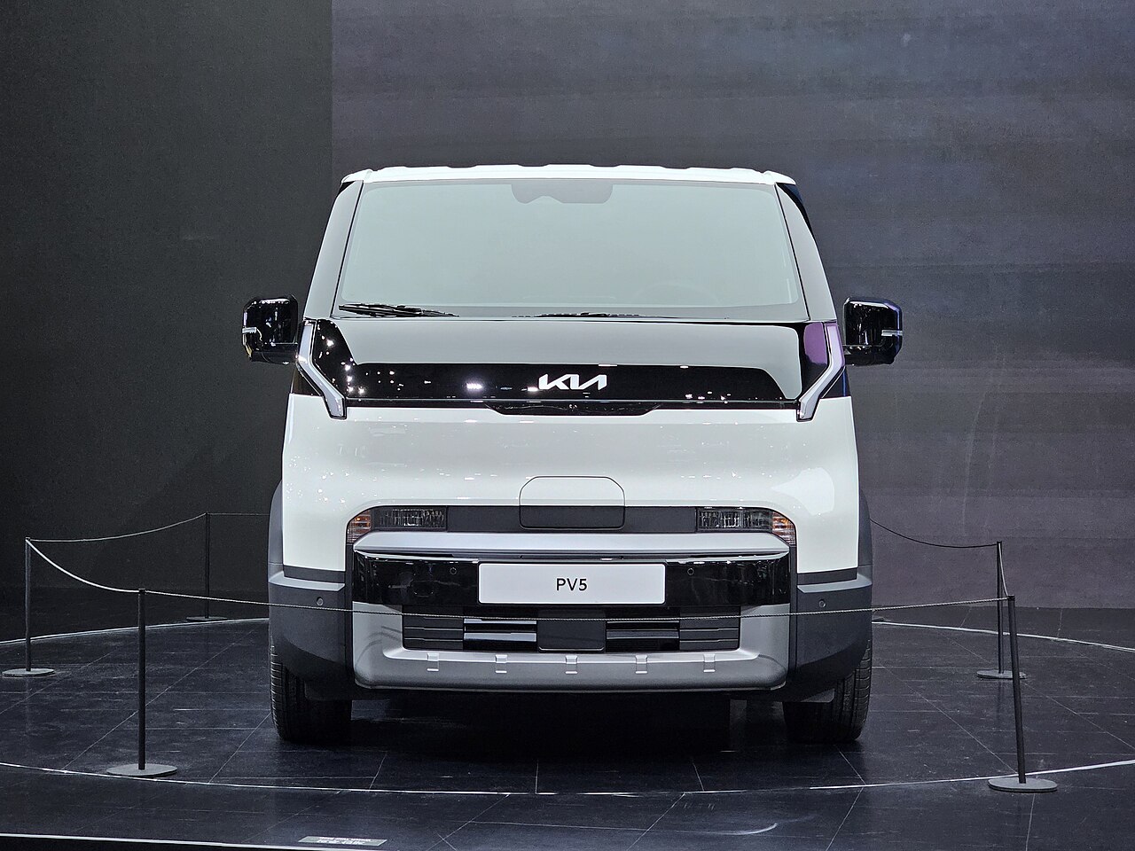 Kia PV5 Cargo รถตู้ไฟฟ้าสีขาว มุมตรงด้านหน้า จัดแสดงบนเวที