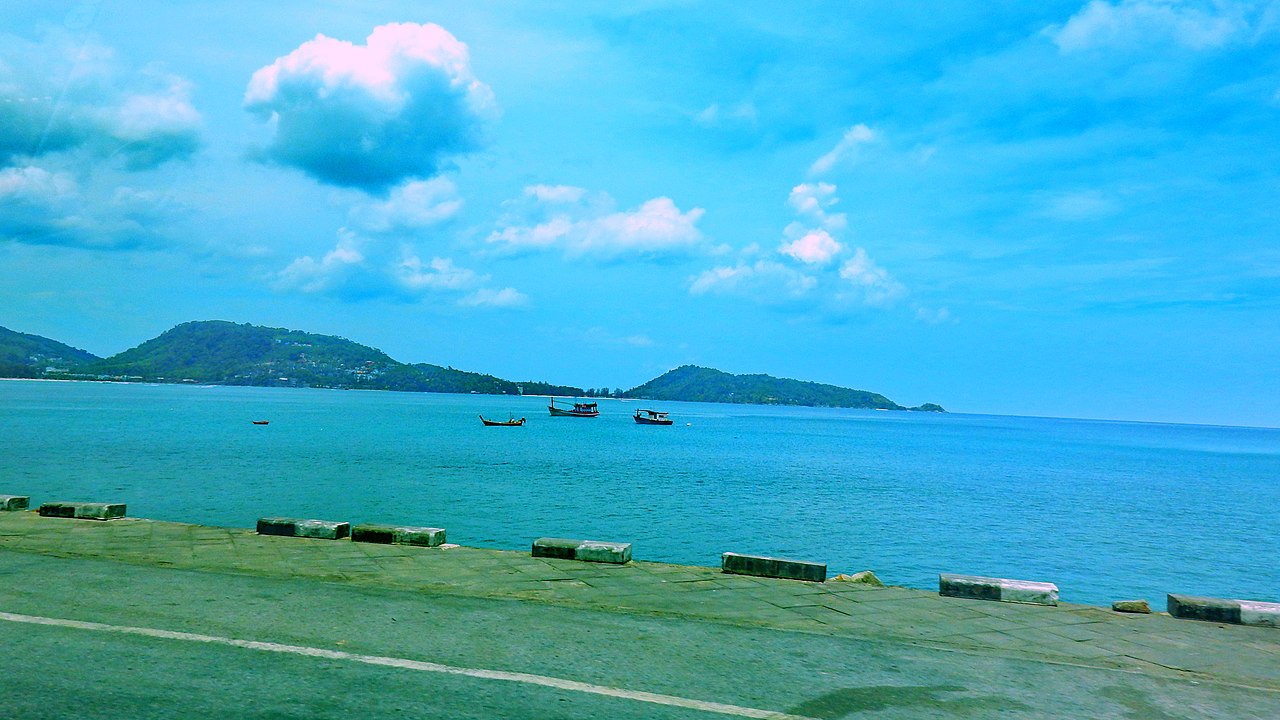 ถนนเลียบทะเลย่านหาดกะหลิม มองข้ามอ่าวป่าตอง เห็นเรือประมงลอยลำ