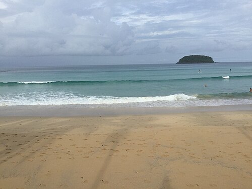 หาดกะตะ ภูเก็ต คลื่นซัดเข้าหาดทราย มีเกาะปูอยู่กลางทะเล