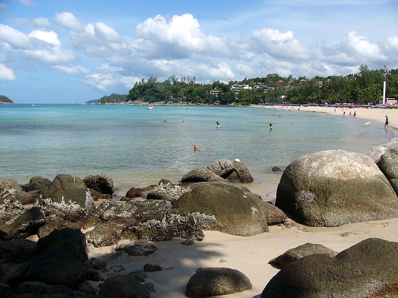 หาดกะตะน้อย ภูเก็ต โขดหินริมหาด น้ำทะเลใส และแนวร่มสีม่วงของรีสอร์ตริมหาด