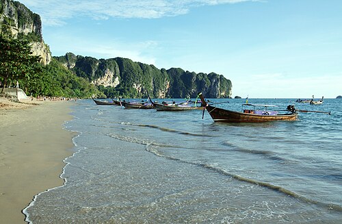 เรือหางยาวจอดริมหาดอ่าวนาง กระบี่ ฉากหลังเป็นหน้าผาหินปูน